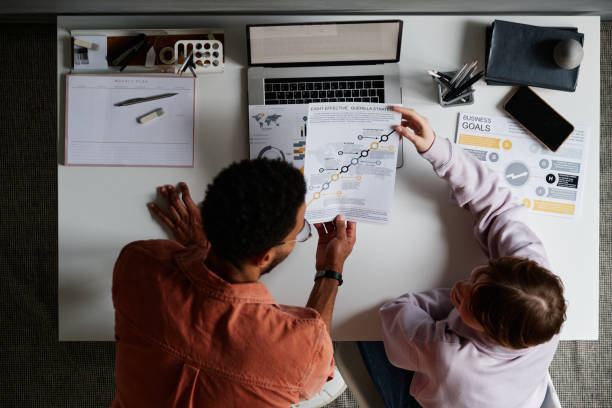 istock High angle view of young multi-ethnic colleagues analyzing papers and discussing strategy in office 1349835788