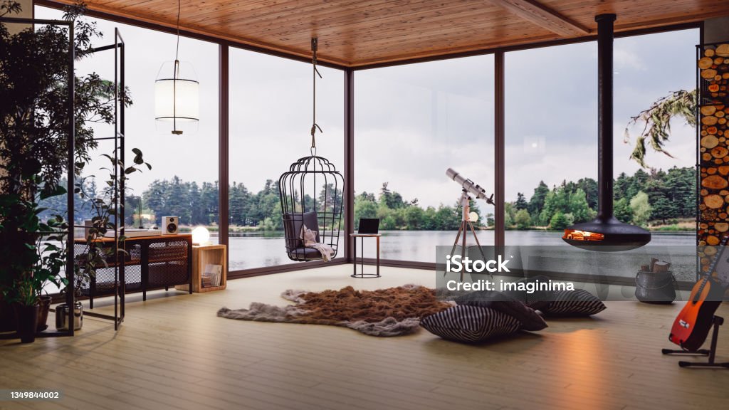 Cozy Lake House Living Room With Lake View Interior of a modern cozy lake house with fireplace and indoor plants. Chalet Stock Photo