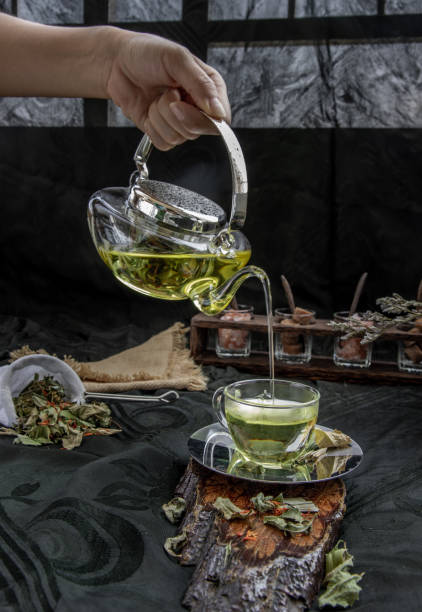 A Hot pandan leaf tea with indian marsh fleabane plant leaves and Safflower dried (Saffron substitute) is poured from the glass teapot into a glass with tea herbal and tea leave. A Hot pandan leaf tea with indian marsh fleabane plant leaves and Safflower dried (Saffron substitute) is poured from the glass teapot into a glass with tea herbal and tea leave. Process brewing tea. Selective focus. substitute for saffron stock pictures, royalty-free photos & images