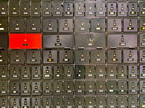 Horizontal wall of black and red numbered residential post office P.O. BOX mail letter boxes in Australia with assigned numbers