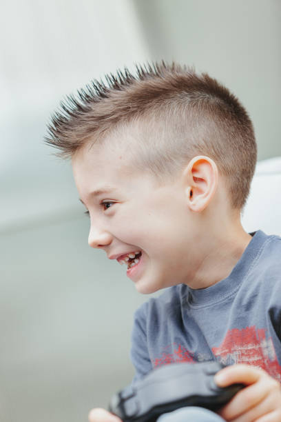 istock Trendy young boy with spiky hair playing video games 1349877103