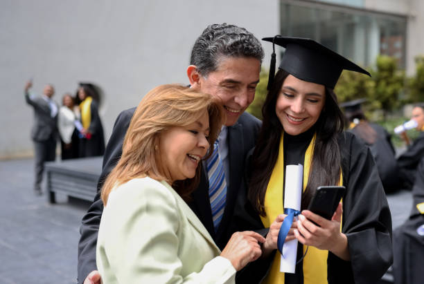 istock Graduating student looking at a picture on her cell phone with her parents 1349878844