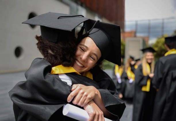 istock Happy students celebrating their graduation with a hug 1349878854