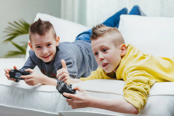 istock Two young brothers playing video games together on the couch 1349880570