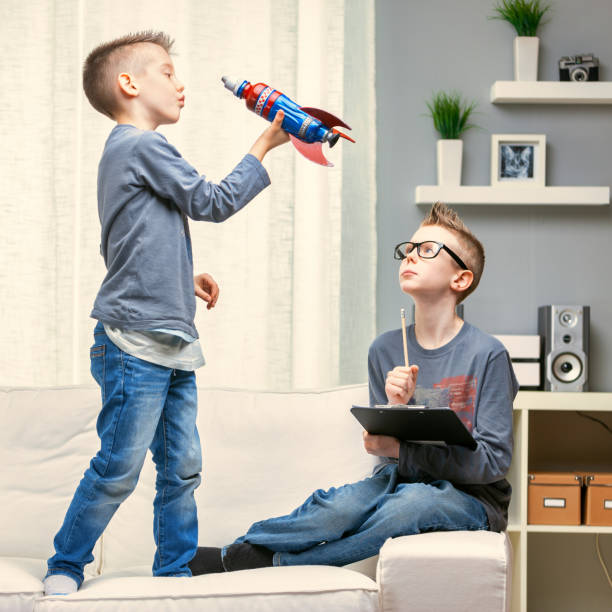 istock Cute young boy playing with a toy rocket on a sofa 1349881284