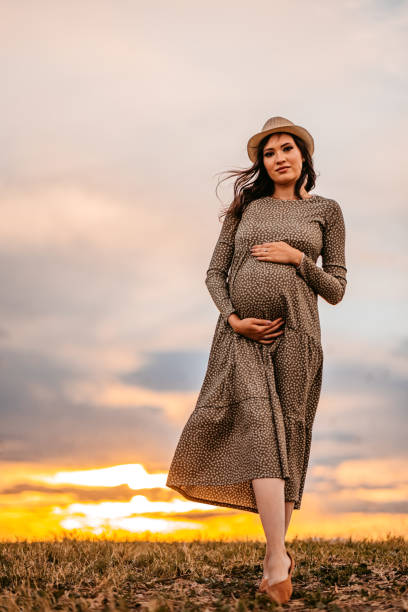 istock Pregnant woman on meadow at sunset 1349896156