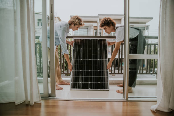 Gay couple are installing solar panel on balcony of the house-stock photo Asian gay couple are settings solar panel  on balcony oft house for environment friendly. balcony stock pictures, royalty-free photos & images