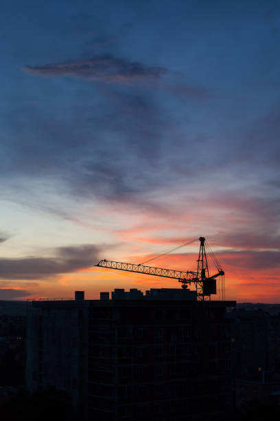 istock Tower crane and building construction site silhouette at sunrise. 1349902622