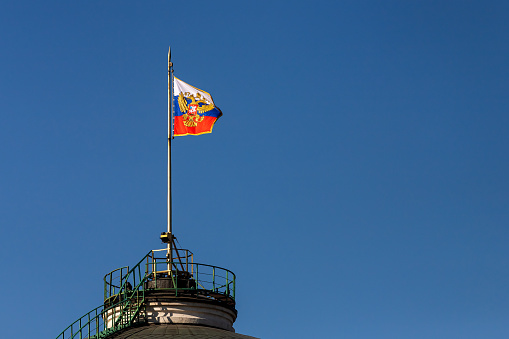 National flag of Russia  on a flagpole waving against blue sky