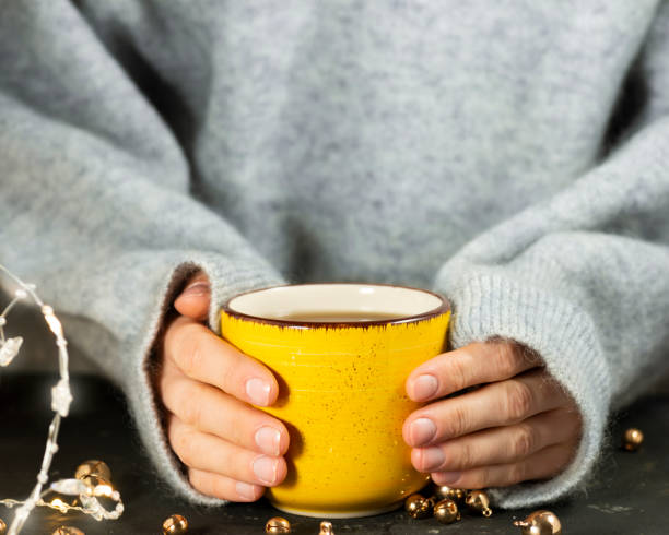 istock Female hands hold a yellow mug with a hot drink tea 1349904830