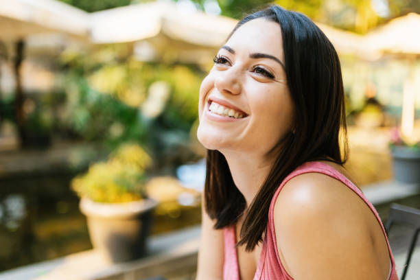 istock Thoughtful hispanic woman sitting alone outdoors - Smiling attractive young girl thinking while looking away - Lady relaxing and enjoying the sun 1349904880