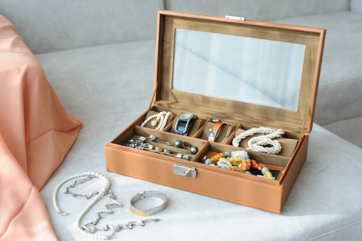 Leather jewelry box with jewelry and accessories laid on a couch with sunlight come from window
