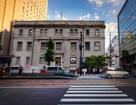 Hiroshima, Hiroshima Prefecture, Japan - October 9, 2021: People at the crosswalk in front of the Former Bank of Japan Hiroshima Branch, one of the few buildings to survive near ground zero of the atomic bomb blast.
