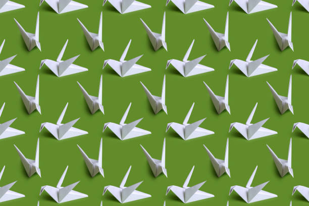 single light green origami paper crane on yellow background with copy space\nstudio shot with NIKON D500