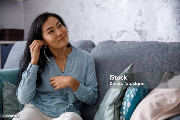 Smiling Young Woman Putting Headphones In To Listen To Music Stock Photo - Download Image Now