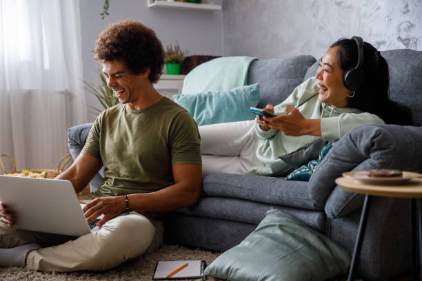 istock Cheerful couple having a laugh while lounging together and using technology 1349910484