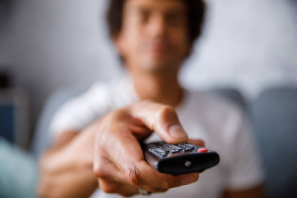 istock Close up shot of man changing channels on TV with a remote control 1349910730