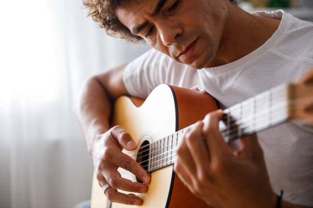 istock Young man concentrating while playing acoustic guitar 1349910807