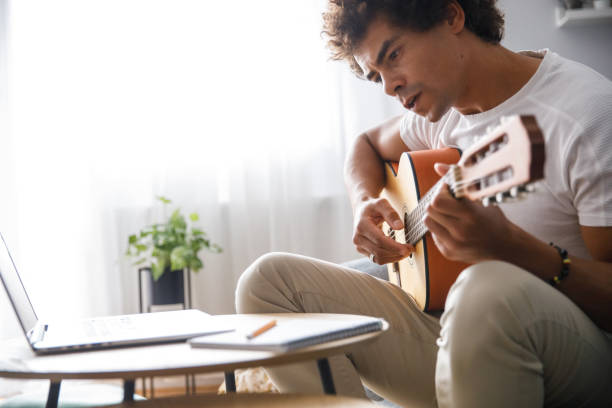 istock Man reading chords he wrote and playing acoustic guitar 1349910808