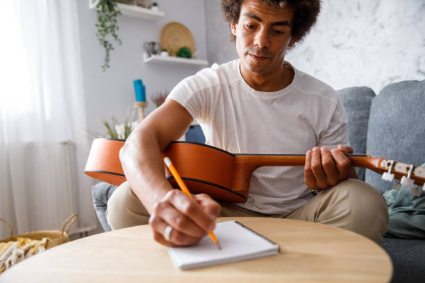 istock Young man composing a song for acoustic guitar and writing chords 1349910818