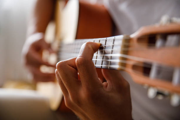 istock Man holding a chord on acoustic guitar while playing a song 1349910822
