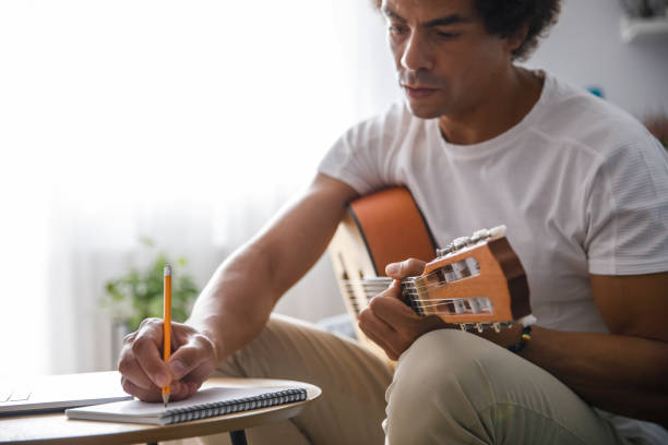 istock Musician composing a song for acoustic guitar and writing down chords 1349910824