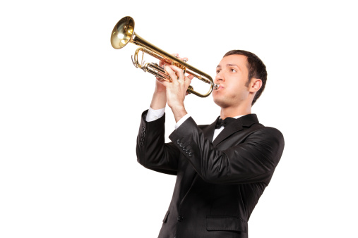 A young man in black suit playing a trumpet isolated on white background
