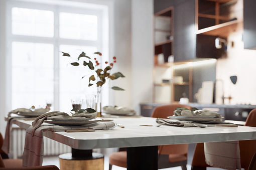 Close-up view of dining set detail, and modern kitchen in bokeh background.