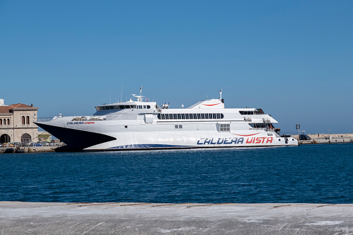 Syros Island, Cyclades, Greece -09.27.2021: Transportation concept. Greek ferry series. Different cargo and passenger ships. High speed catamaran traveling and connecting Aegean Islands with main land. Nautical background with copy space