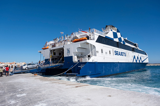 Syros Island, Cyclades, Greece -09.27.2021: Transportation concept. Greek ferry series. Different cargo and passenger ships. High speed catamaran traveling and connecting Aegean Islands with main land. Nautical background with copy space