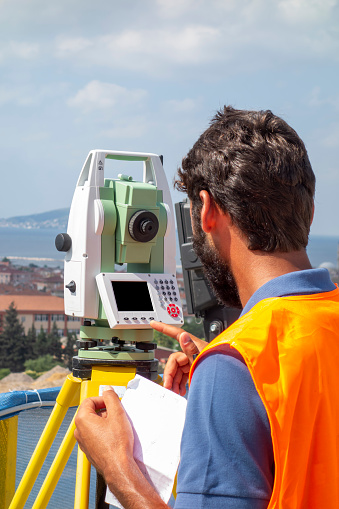 A male engineer works with the optical level on site