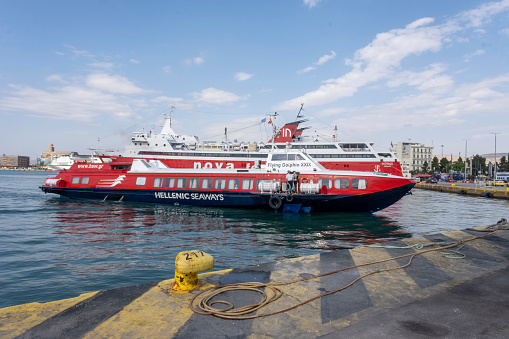 Piraeus, Athens, Greece - 09.29.2021: Transportation concept. Greek ferry series. Different cargo and passenger ships. High speed catamaran traveling and connecting Aegean Islands with main land. Nautical background with copy space