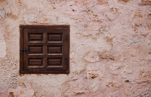 Closeup of small wooden window on stone wall in Ayllon, Castilla y Leon, Spain
