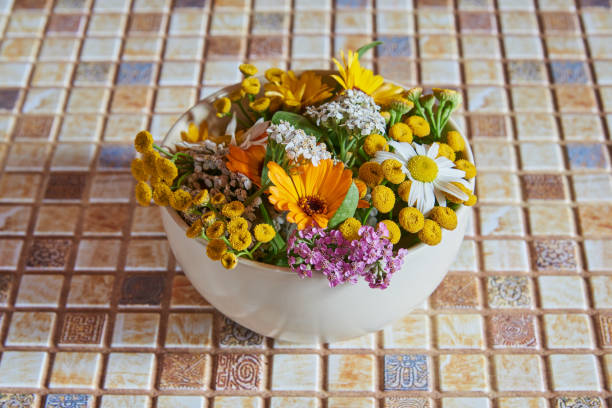 A ceramic bowl with medicinal herbs and flowers is on the countertop. Alternative medicine.