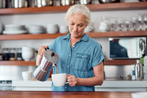 Shot of a mature woman making coffee in the kitchen at home