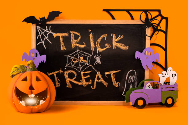istock Happy halloween holiday concept. Jack o lantern, handmade paper decorations, ghosts, bat, spider, web, trick or treat text on chalkboard frame on orange background. Halloween festival, greeting card 1349923541