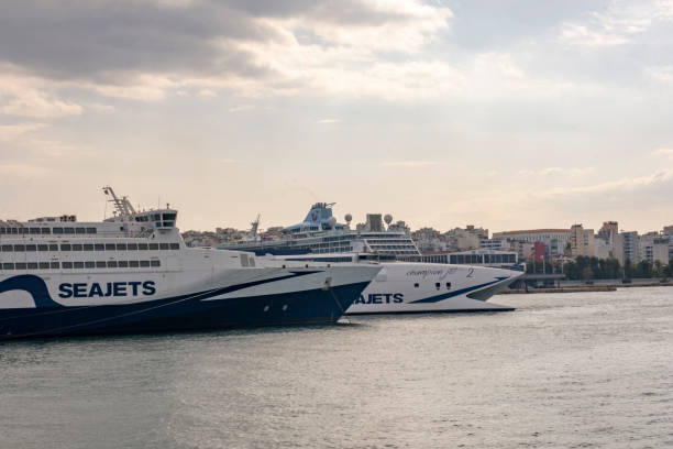 Piraeus, Athens, Greece - September 29, 2021: Transportation concept. Greek ferry series. Two SEAJETS ships moored next to each other at Piraeus port in front of city. Nautical background with copy space