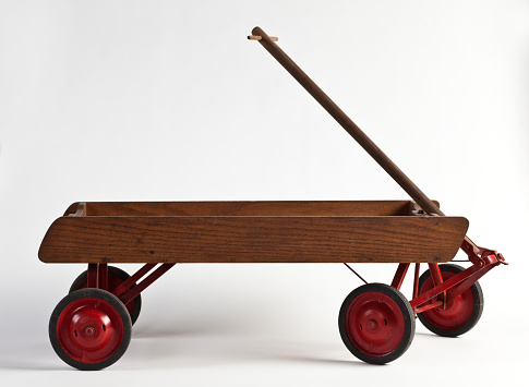 Studio shot of wooden wagon with red wheels on a white background.