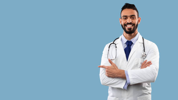 Middle-Eastern Male Doctor Pointing Finger Aside At Copyspace, Studio Shot stock photo