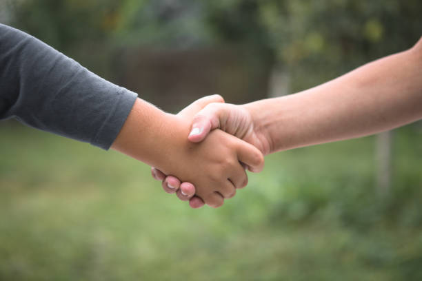 istock Beautiful Peace Symbol - Child Holding Hands. Handshake boys 1349936595