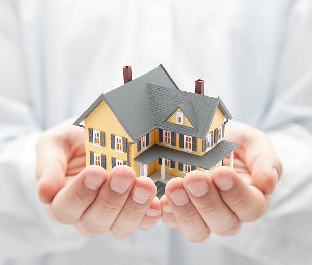 istock Yellow model house in two cupped hands 134993947