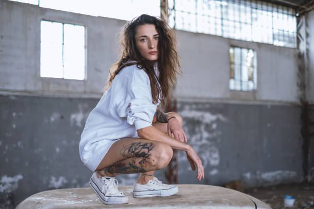 Young woman in abandoned building and standing on a scrap car .