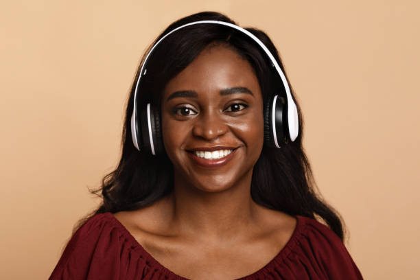 istock Positive black lady listening to music, using wireless headset 1349943693