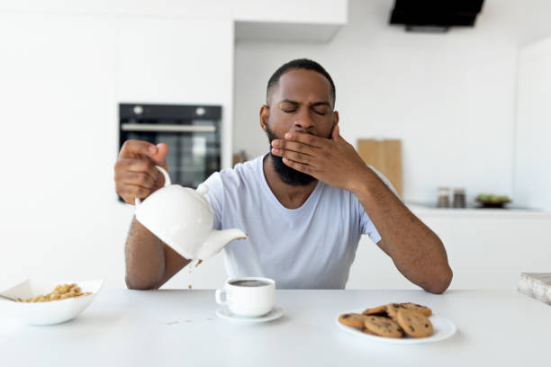 istock Black guy pouring coffee away from cup and yawning 1349946282