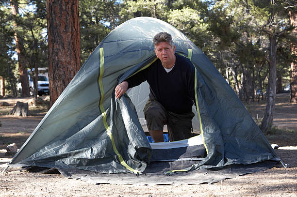 istock Man emerging from tent in the woods 134995279