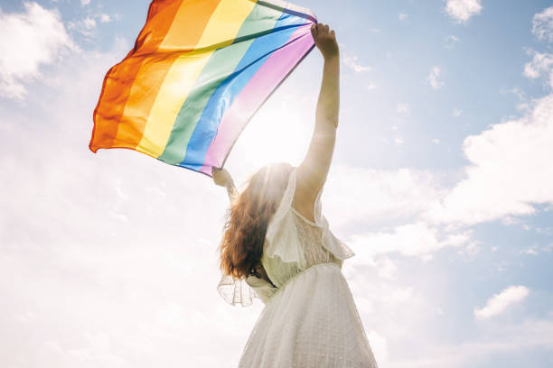 istock Woman with rainbow flag on sky background. 1349955052
