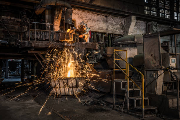 istock Metal worker discharging molten metal into container in foundry 1349955629