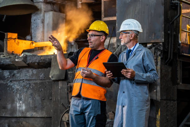 istock Male engineers discussing while standing in the foundry. 1349955664