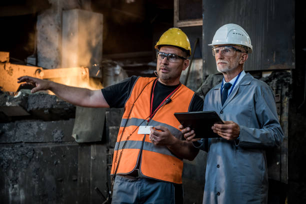 istock Male engineers discussing while standing in the foundry. 1349955665