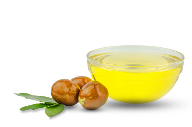 bol con aceite de jojoba y frutas maduras sobre fondo blanco - aceites esenciales fotografías e imágenes de stock